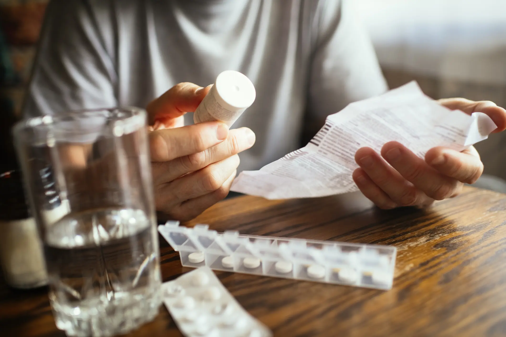 Person reading medication instructions while holding a pill bottle.