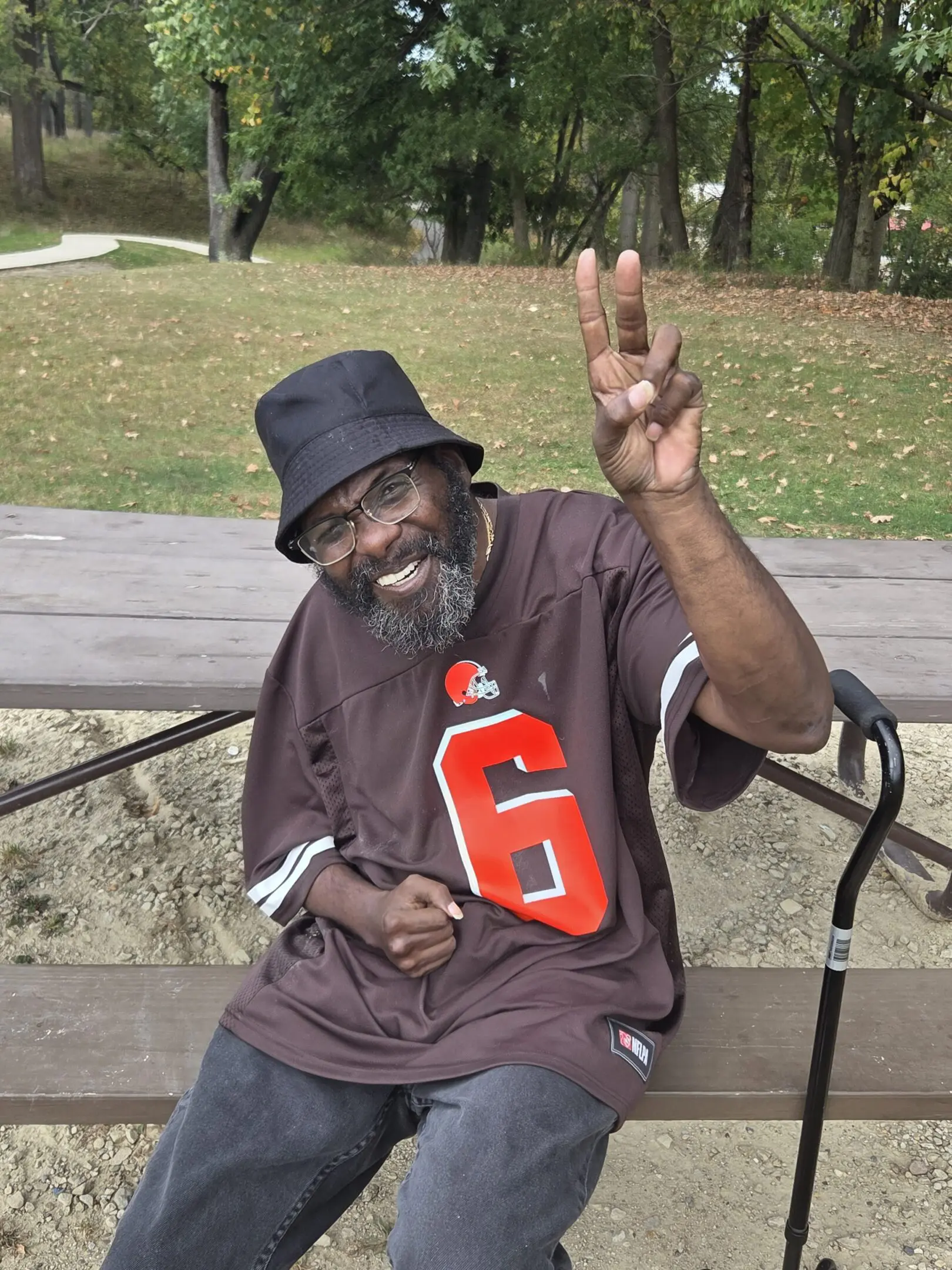 Man in a black bucket hat and oversized shirt making a peace sign.