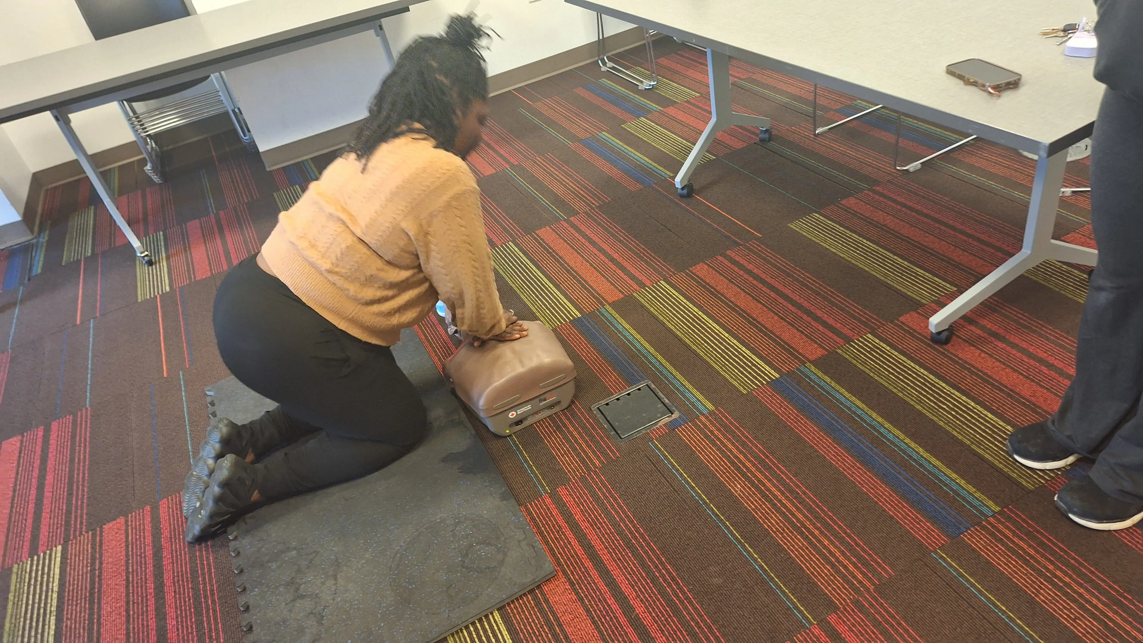 Person practicing CPR on a training mannequin indoors.